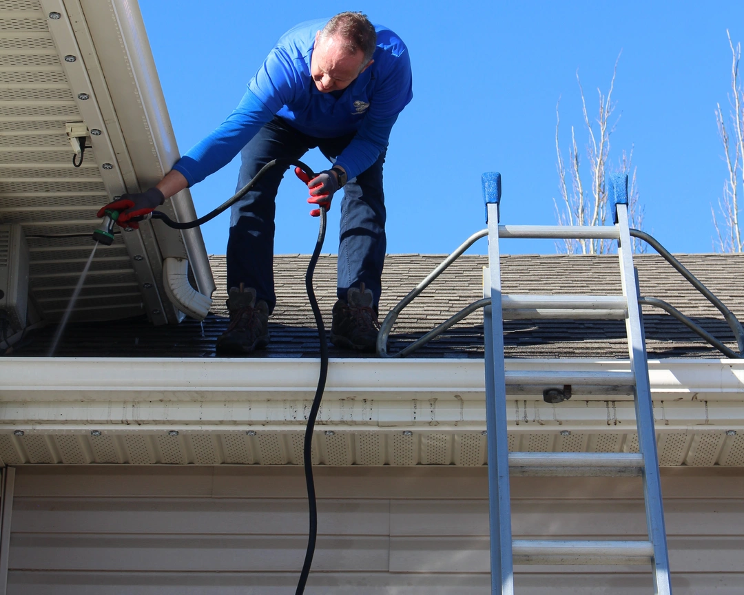 Kyle using a hose to clean out gutters