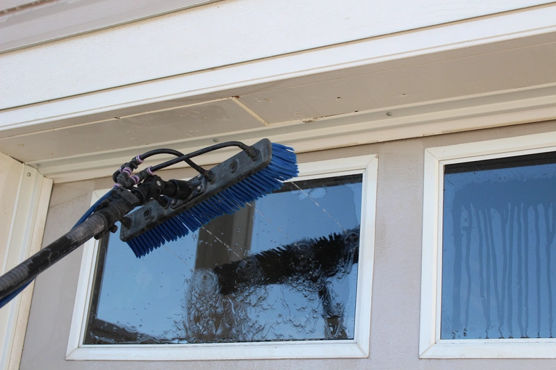 Close-up shot of a professional window cleaning brush scrubbing a garage door window, showing the effective tools used by Calgary's A Touch Of Glass team.